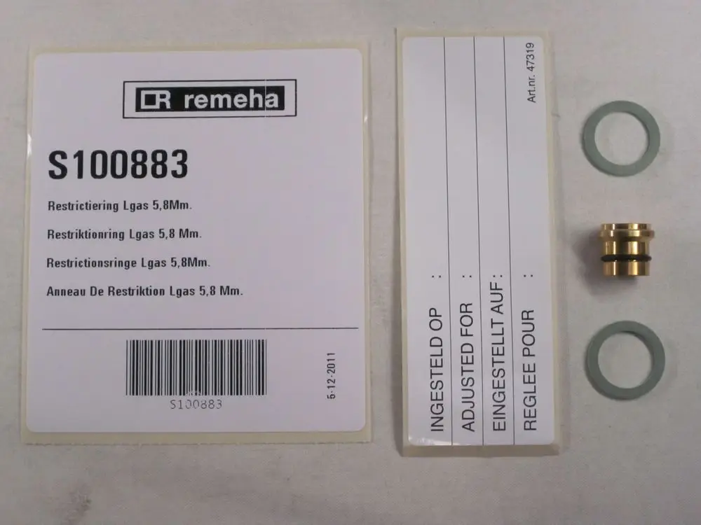 Zwei Produktetiketten von Remeha, ein goldfarbener Drosselring mit O-Ringen sowie eine beige Packung mit Barcode, alle auf einer neutralen Oberfläche angeordnet.